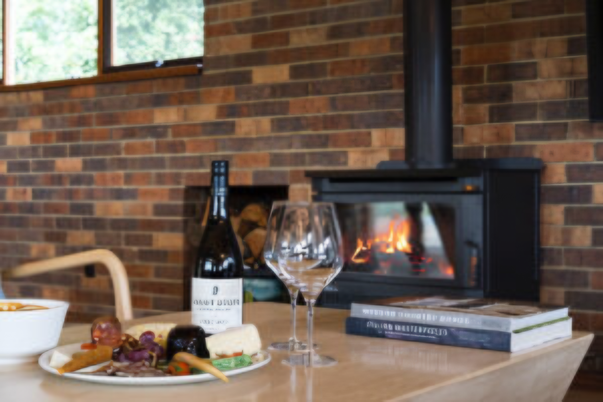 Local wine, cheese platter and wood fireplace inside luxury Langbrook Farm accommodation in the Yarra Valley